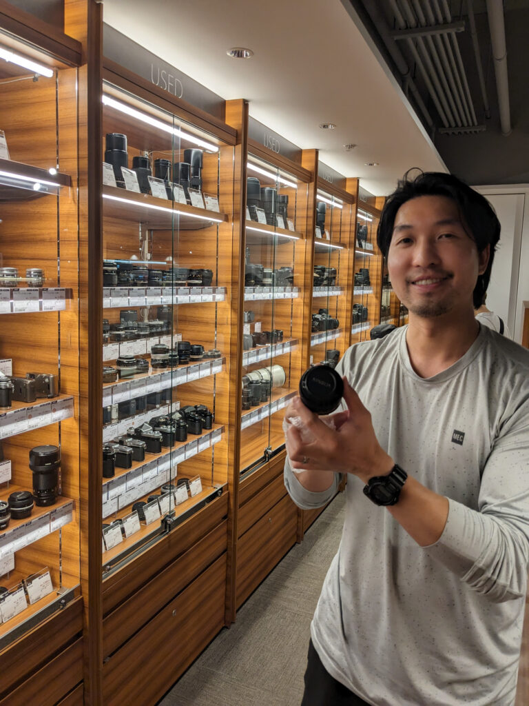 Me holding a new purchase, the Minolta 28mm in Osaka camera store